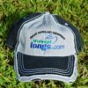 black and gray ball-cap with Midwest Tong's logo laying on grass