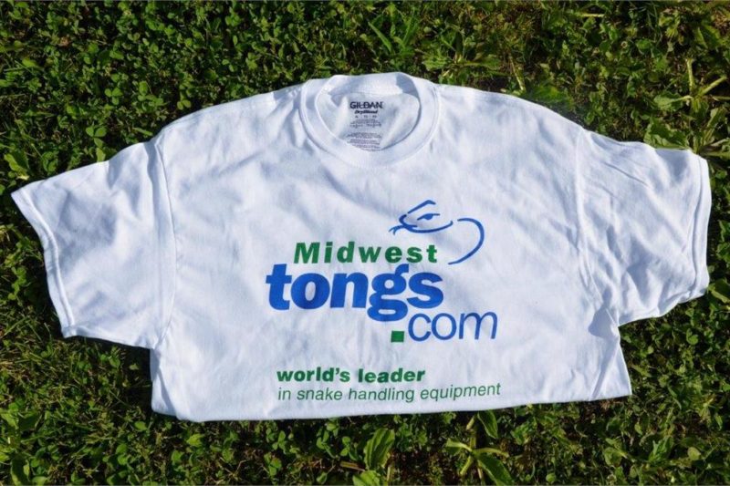 white folded t-shirt with Midwest Tong's logo laying on grass