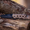 copper and black emergency knife balanced on logs